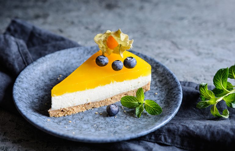 Homemade no bake mango cheesecake decorated with blueberries and physalis